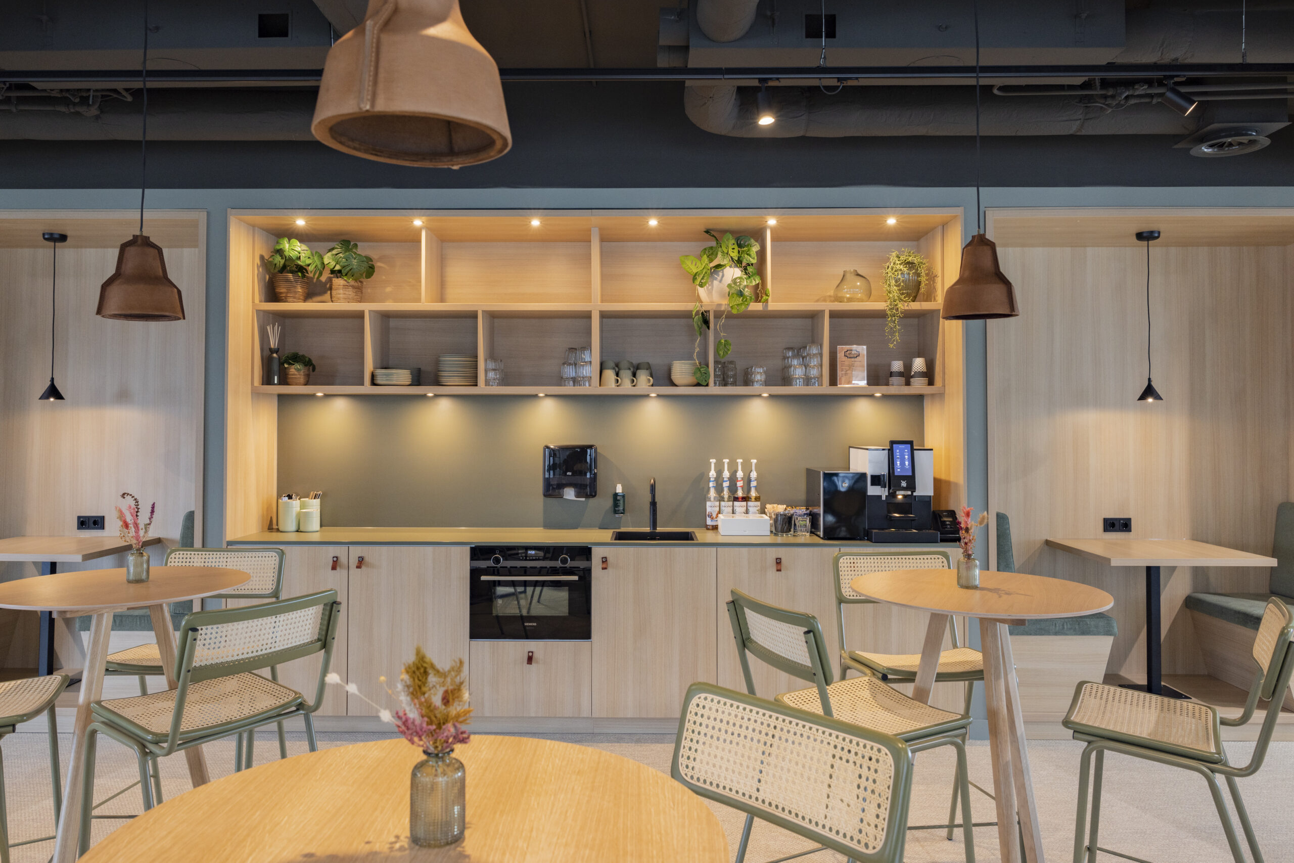 Een moderne kantoorruimte met houten meubels, groene accenten en planten tegen de muur.