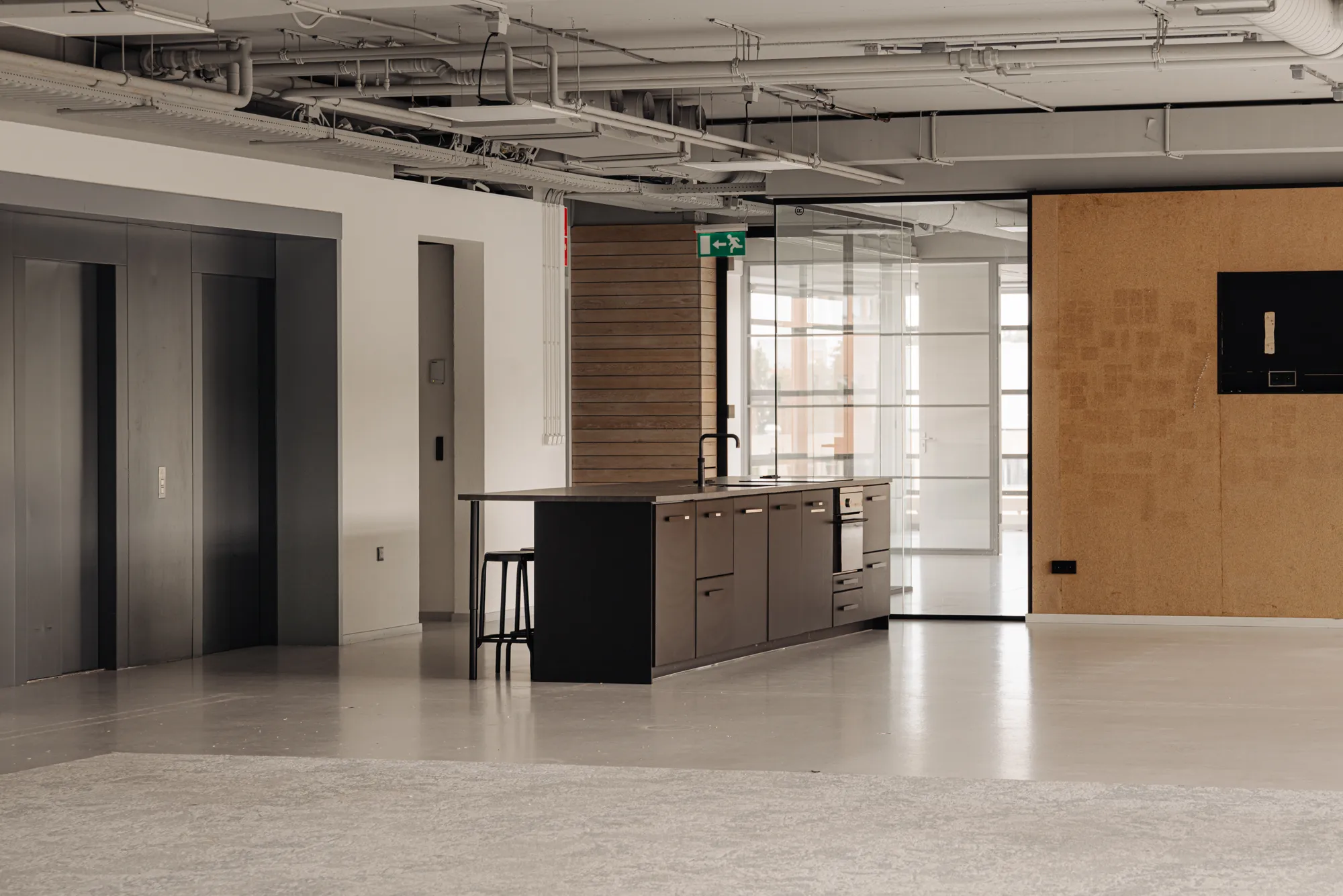 Een moderne, minimalistische kantoorruimte met een keuken en glazen wanden.