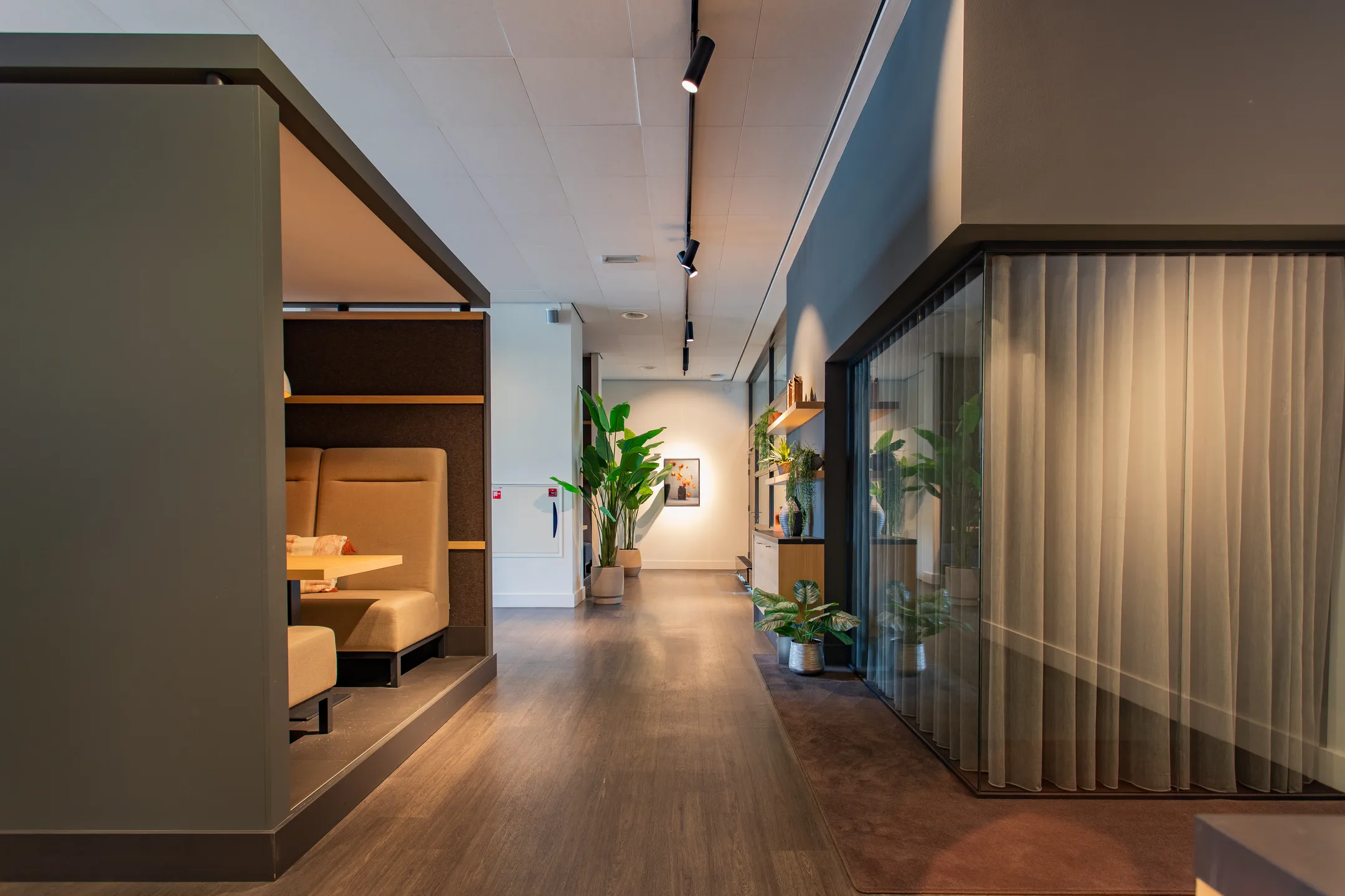 Een moderne kantoorruimte met een zitgedeelte, planten en glazen wanden.