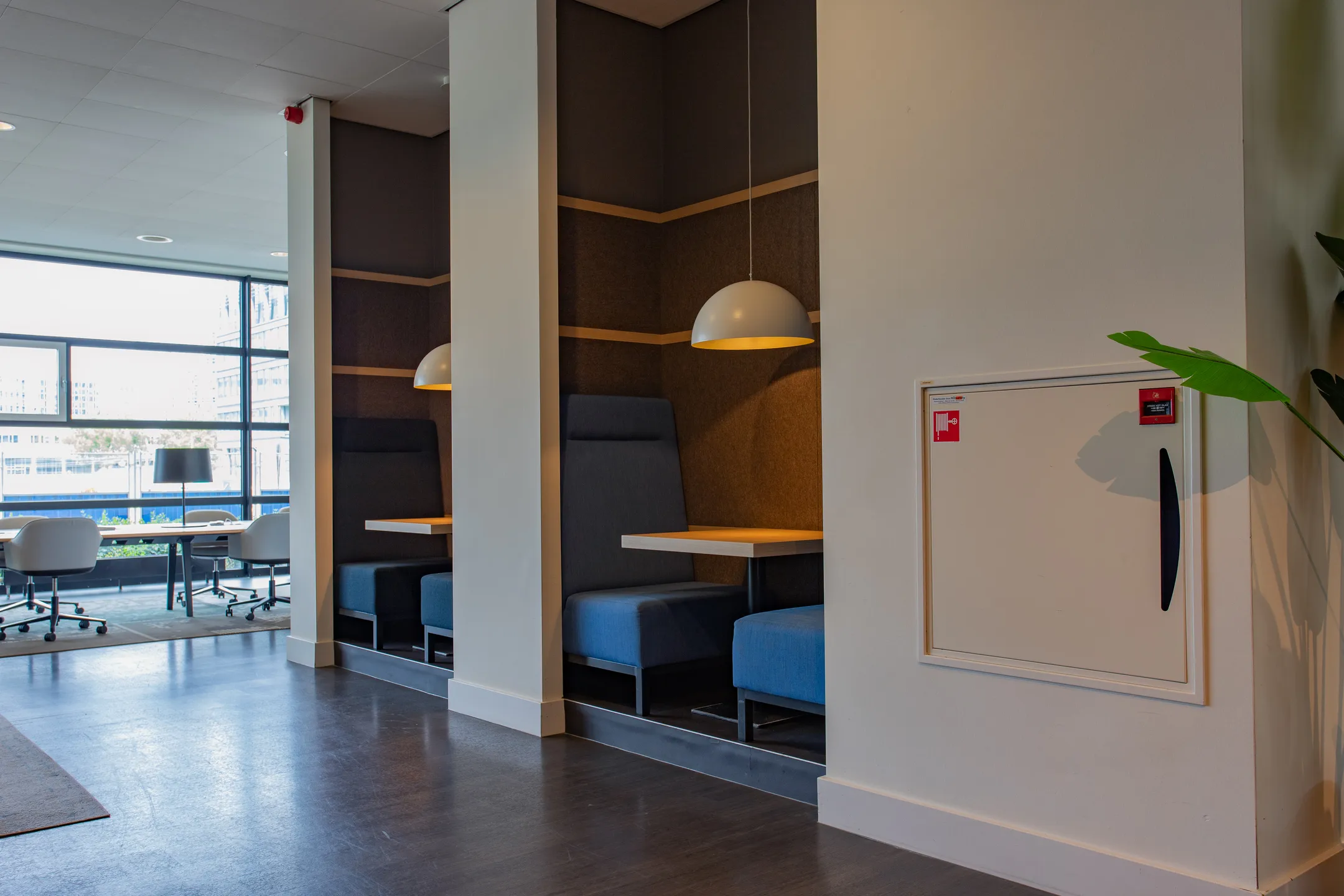 Moderne kantoorruimte met ingebouwde zitplekken en bureaus bij grote ramen.