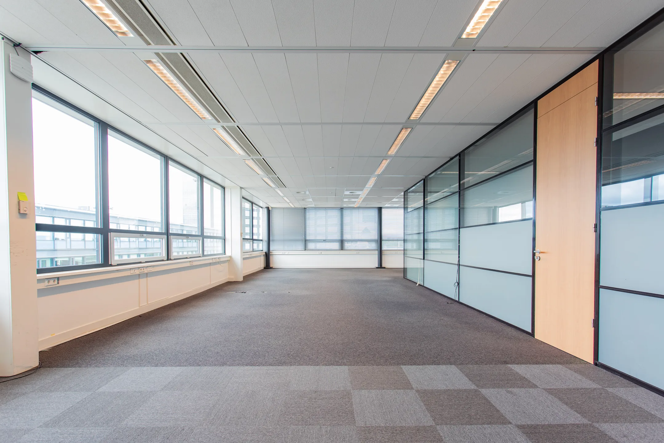 Leeg, modern kantoor met grote ramen en glazen wanden.