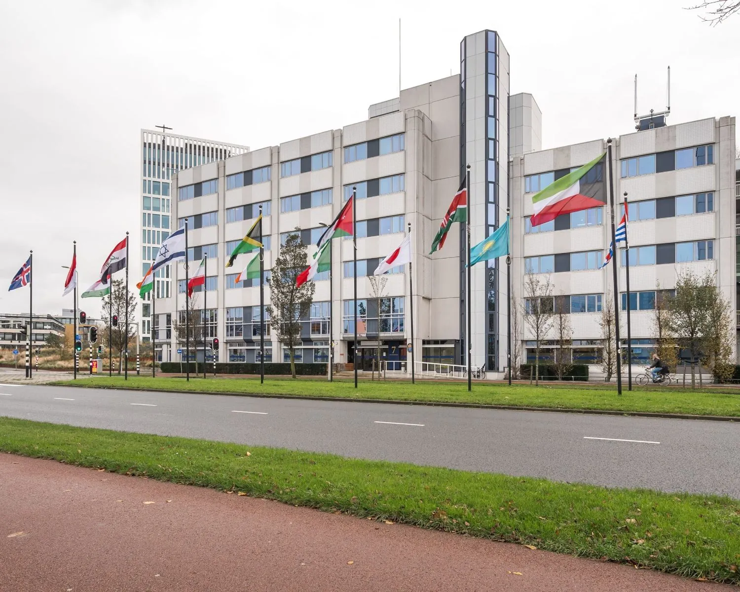 Kantoorgebouw 5443_1 met internationale vlaggen ervoor langs een weg en fietspad.