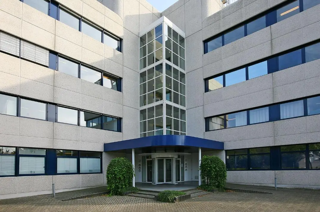 Ingang van een modern kantoorgebouw aan de Vreeswijksestraatweg met grijze gevel, blauwe raamkozijnen en glazen entreepartij.