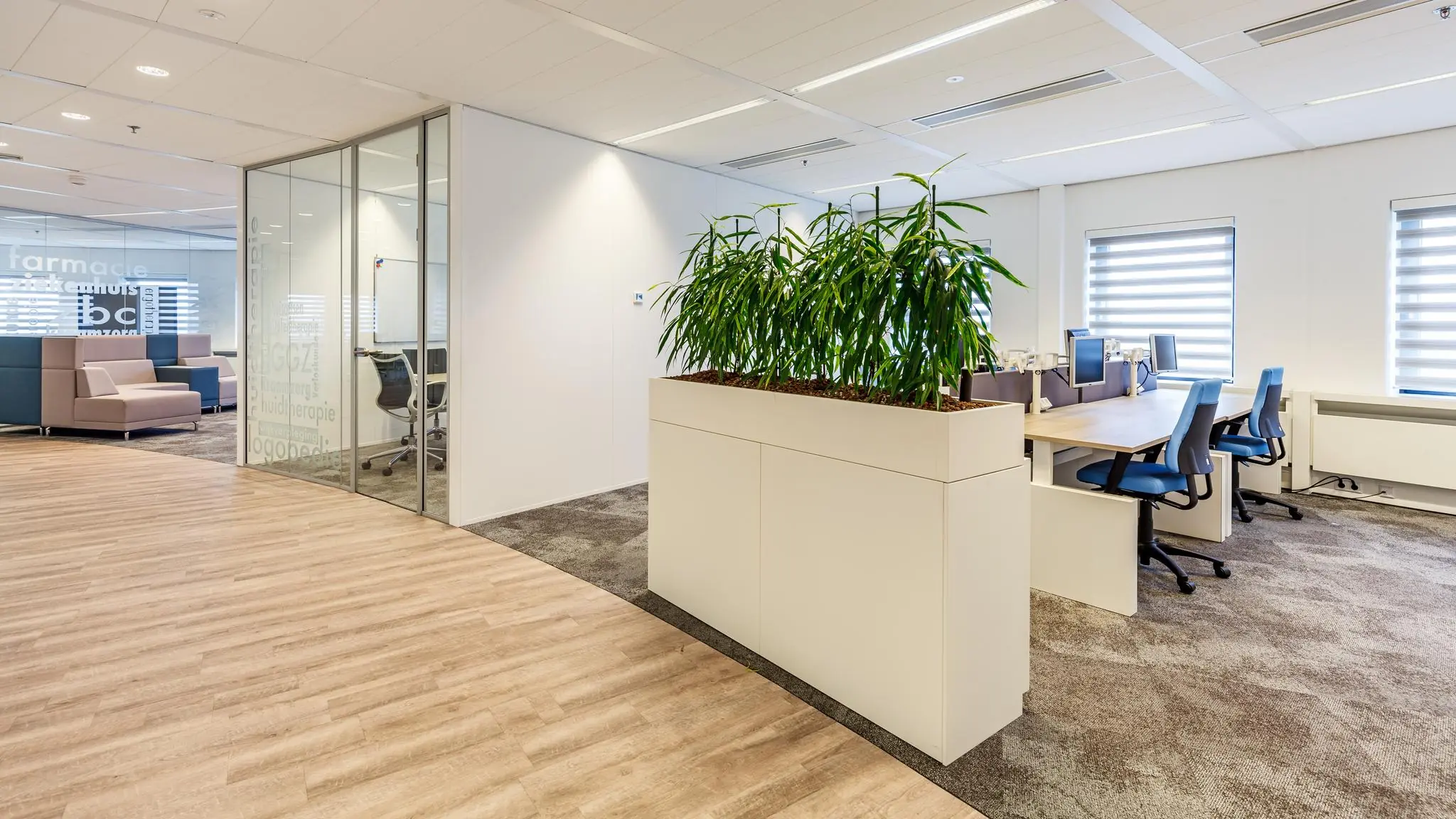 Moderne kantoorruimte aan de Euclideslaan met werkplekken, vergaderruimte en een grote plantenbak als sfeerelement.