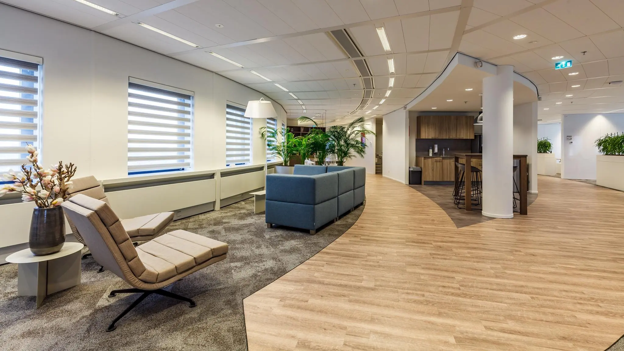 Moderne lounge- en ontmoetingsruimte in een kantoor aan de Euclideslaan met zitplaatsen, planten en een koffiecorner.