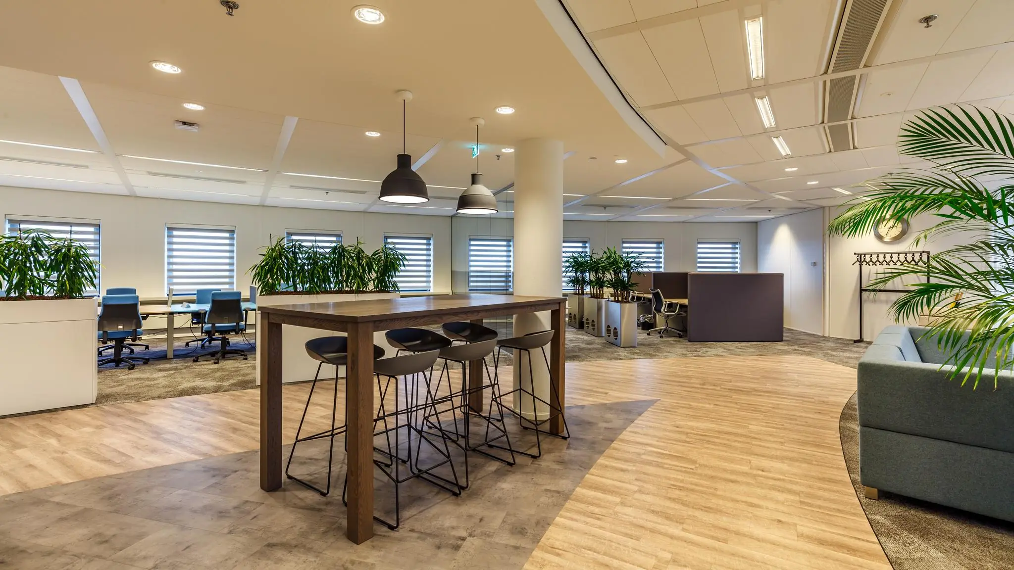 Moderne, open kantoorruimte aan de Euclideslaan met flexibele werkplekken, hoge tafel, zithoeken en veel groen.