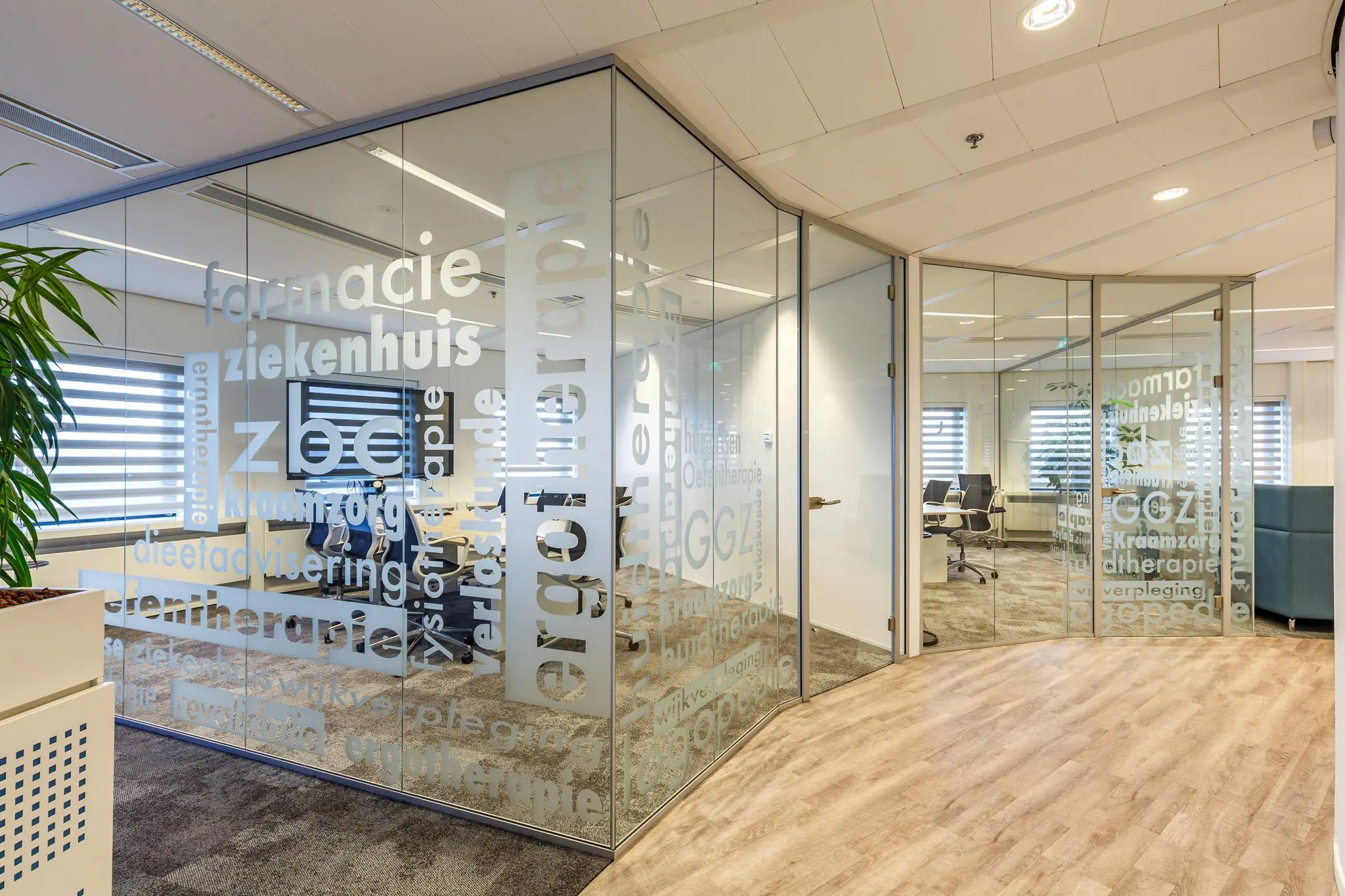 Moderne kantoorruimte aan de Euclideslaan met glazen wanden bedrukt met zorggerelateerde woorden.