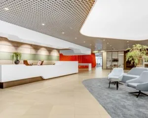 Moderne en stijlvolle ontvangsthal van kantoorpand Delftse Poort aan het Weena 505 in Rotterdam met balie, zitgedeelte en opvallend rood accent.