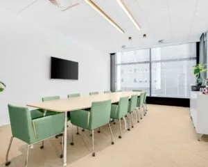 Moderne vergaderruimte in Delftse Poort in Rotterdam met lange tafel, groene stoelen en een groot raam met stadszicht.