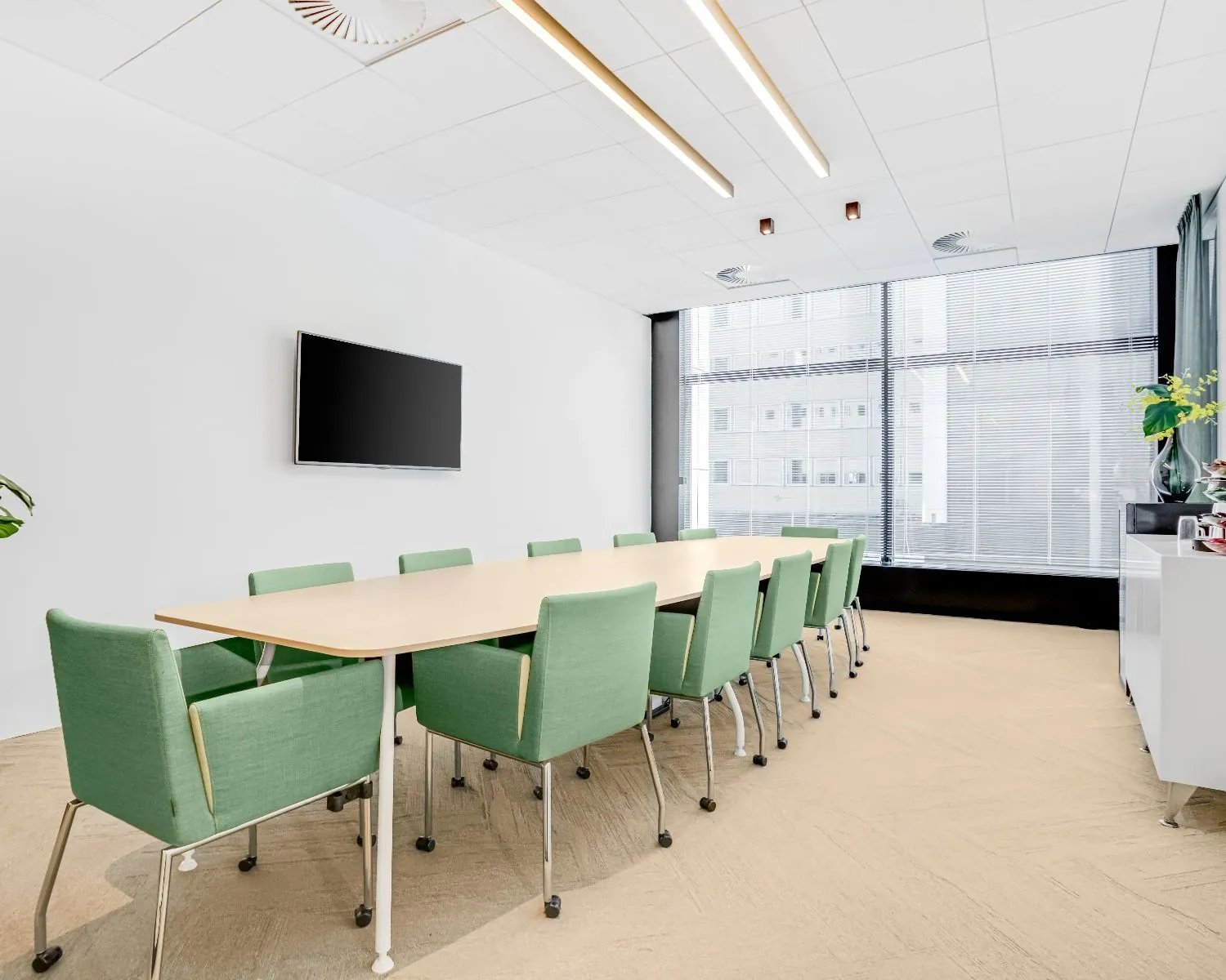 Moderne vergaderruimte in Delftse Poort in Rotterdam met lange tafel, groene stoelen en een groot raam met stadszicht.