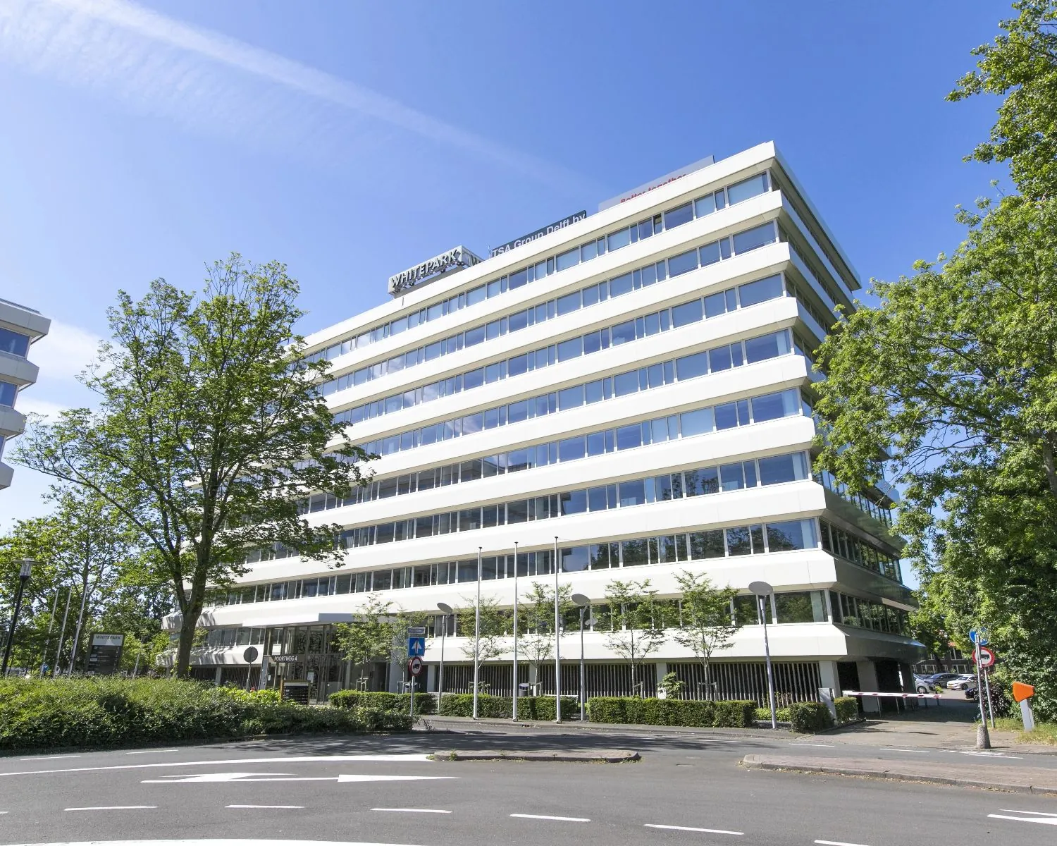 Modern kantoorpand Whitepark aan de Poortweg 4 in Delft, omgeven door groen en gelegen aan een rustige weg.