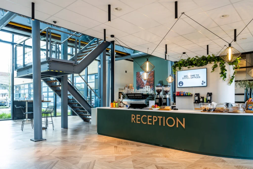 Een moderne receptieruimte met een grote ontvangstbalie en een open trap.