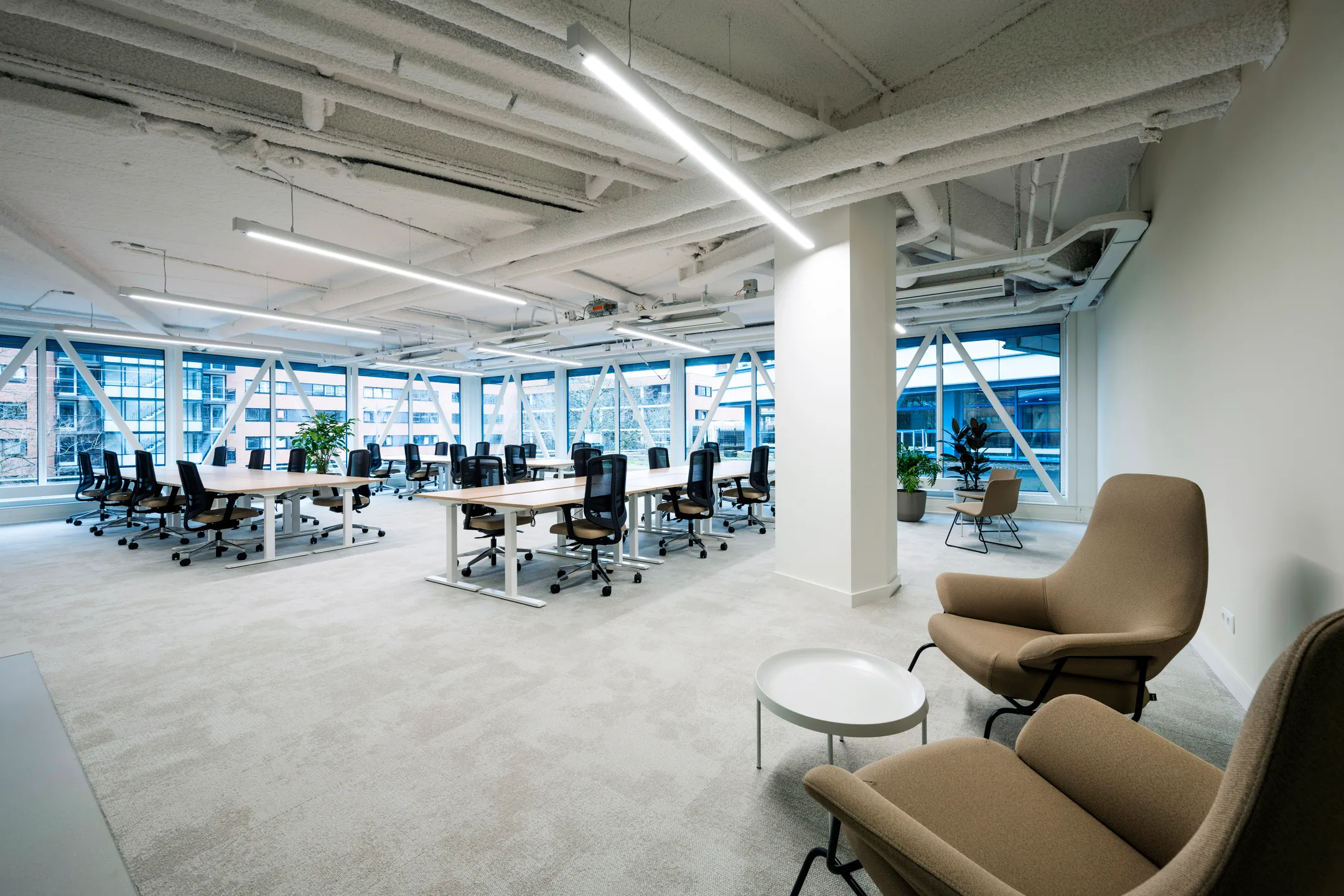 Een moderne en ruime kantoorruimte met bureaus, stoelen en grote ramen.