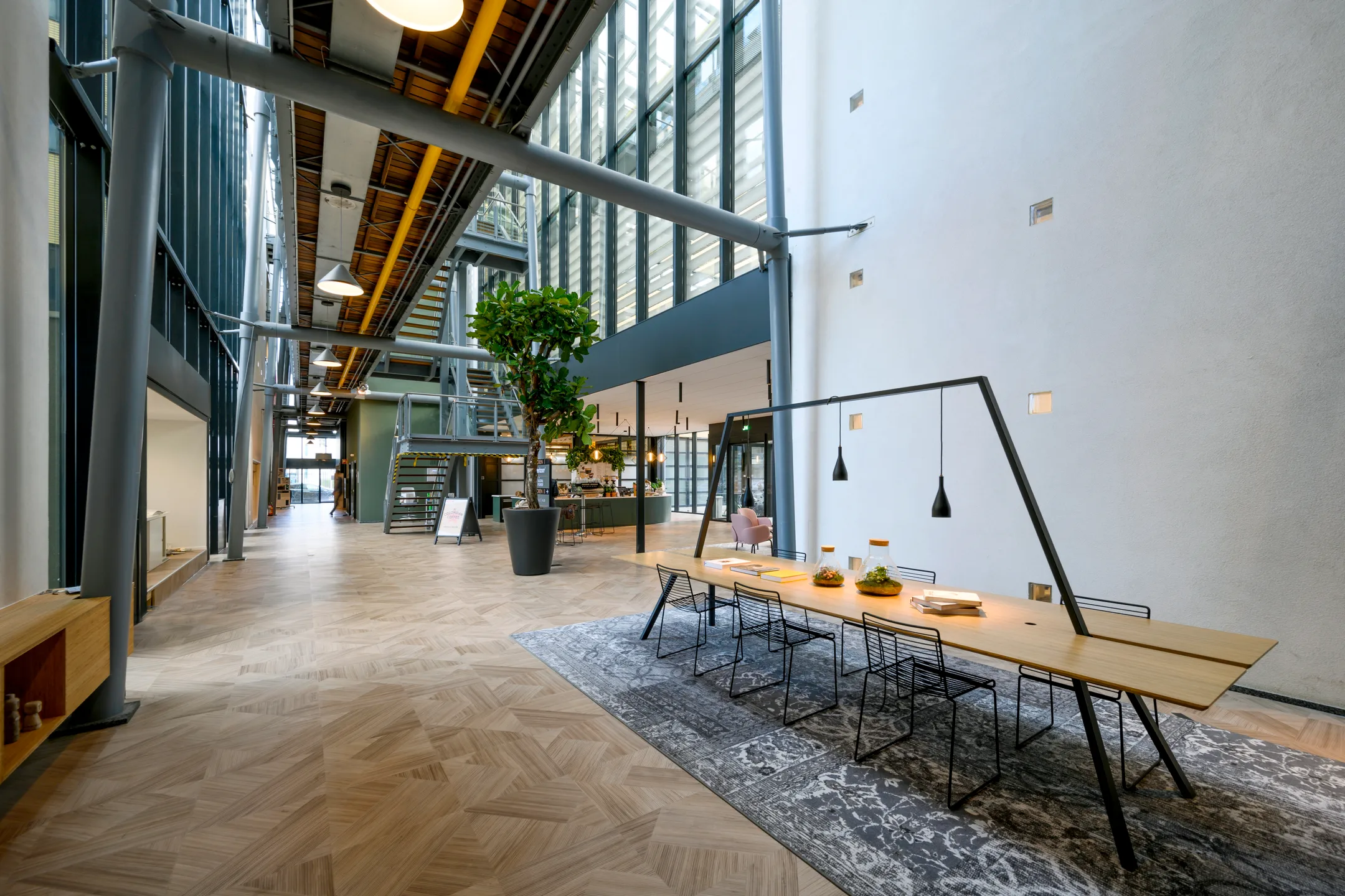 Een moderne kantoorruimte met een lange houten tafel en industriële elementen.