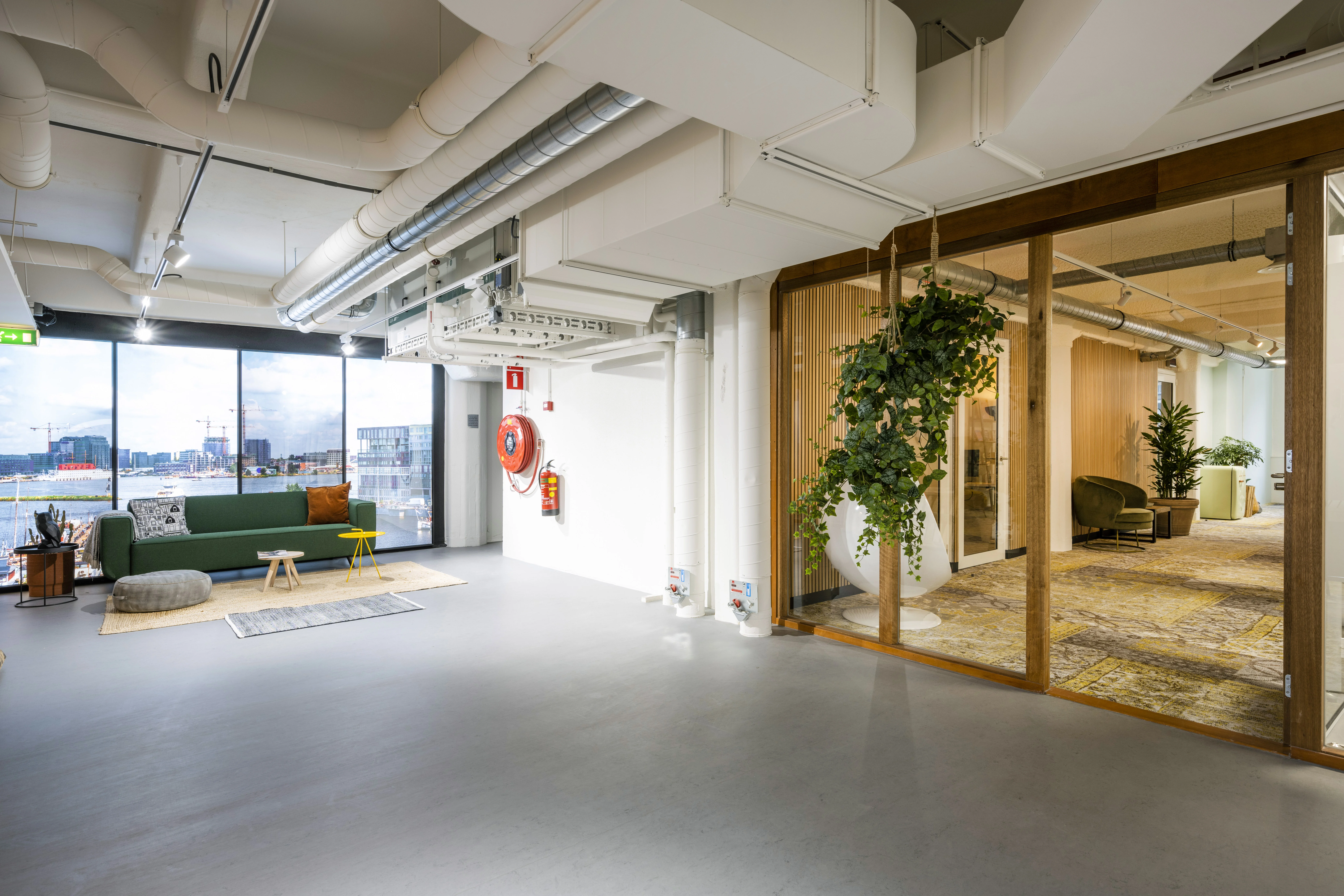 Modern interieur van kantoorruimte HNK in Diemen met zithoek, grote ramen en groene accenten.
