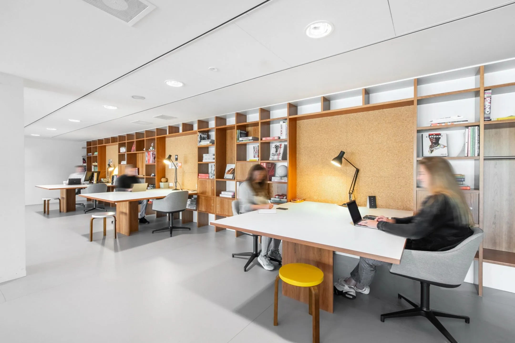 Lichte en moderne vergaderruimte met houten tafels, beige stoelen en bureaulampen in het zachte zonlicht.