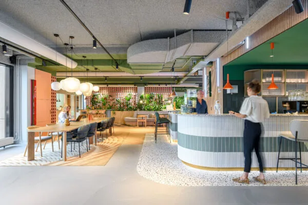 Moderne, kleurrijke kantoorruimte met een open zithoek, werkplekken en een ronde ontvangstbalie.