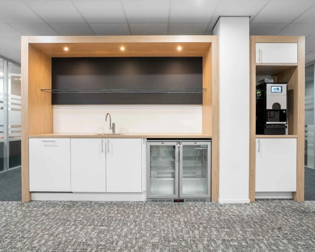 Moderne pantry met inbouwkoelkast, koffiemachine en spoelbak in kantoor aan de Hurksestraat 43 in Eindhoven.