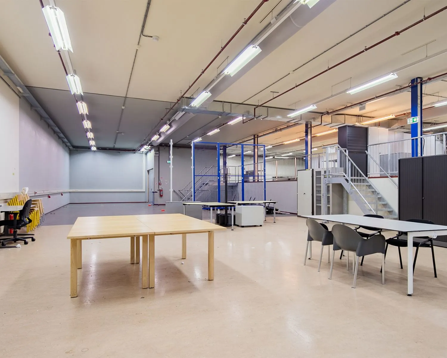 Ruime, industriële kantoorruimte aan de Albert Einsteinweg 5 in Lelystad met bureaus, stoelen en een metalen trap.