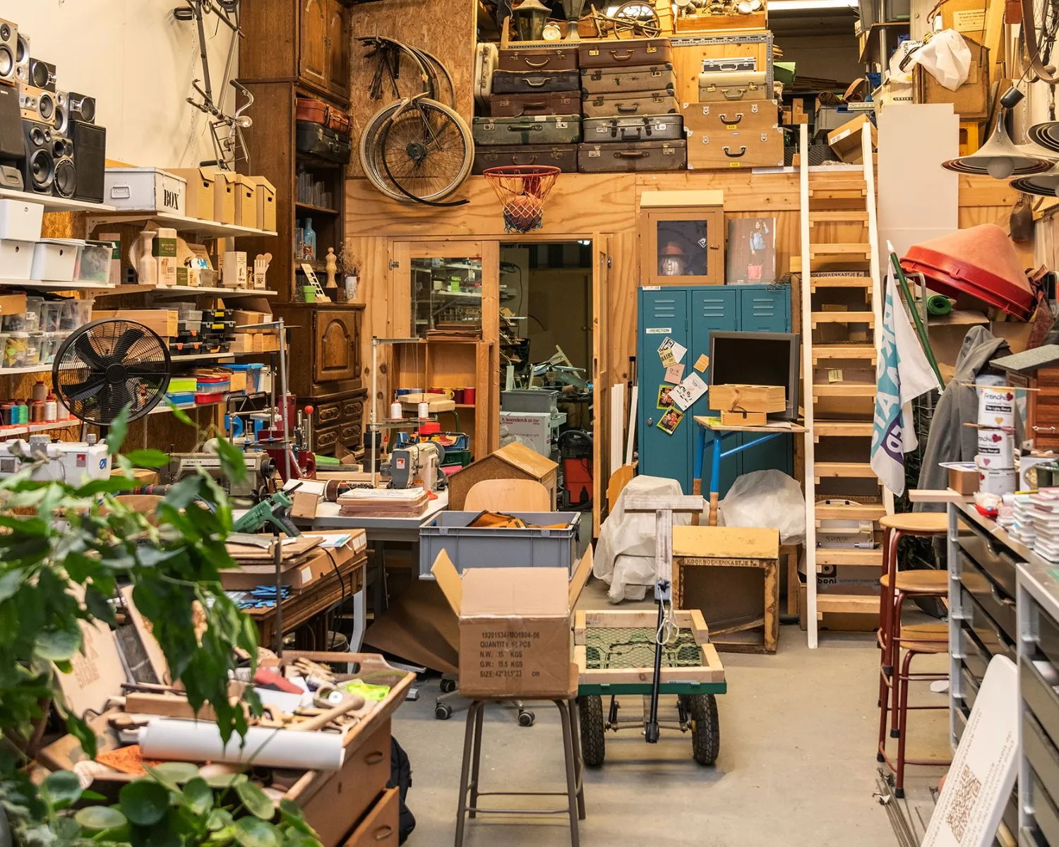 Creatieve en drukke werkruimte in Almere met een mix van vintage meubels, gereedschappen en opbergkasten.