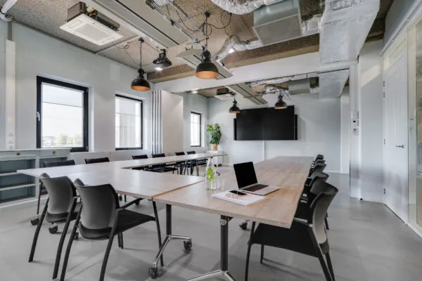 Moderne vergaderruimte op Utrecht Centraal met U-vormige opstelling, laptop, notitieboek en grote presentatieschermen.