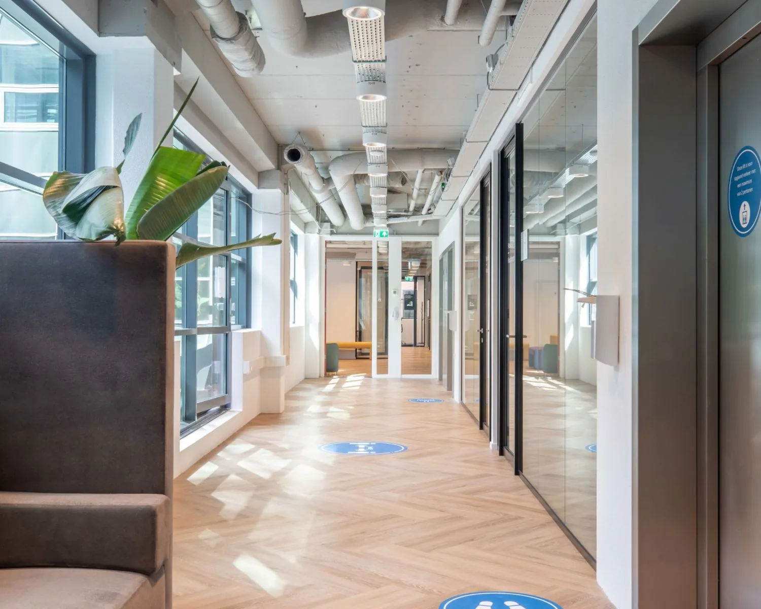 Moderne gang met glazen kantoorwanden in het Coengebouw aan de Kabelweg 37 in Amsterdam.