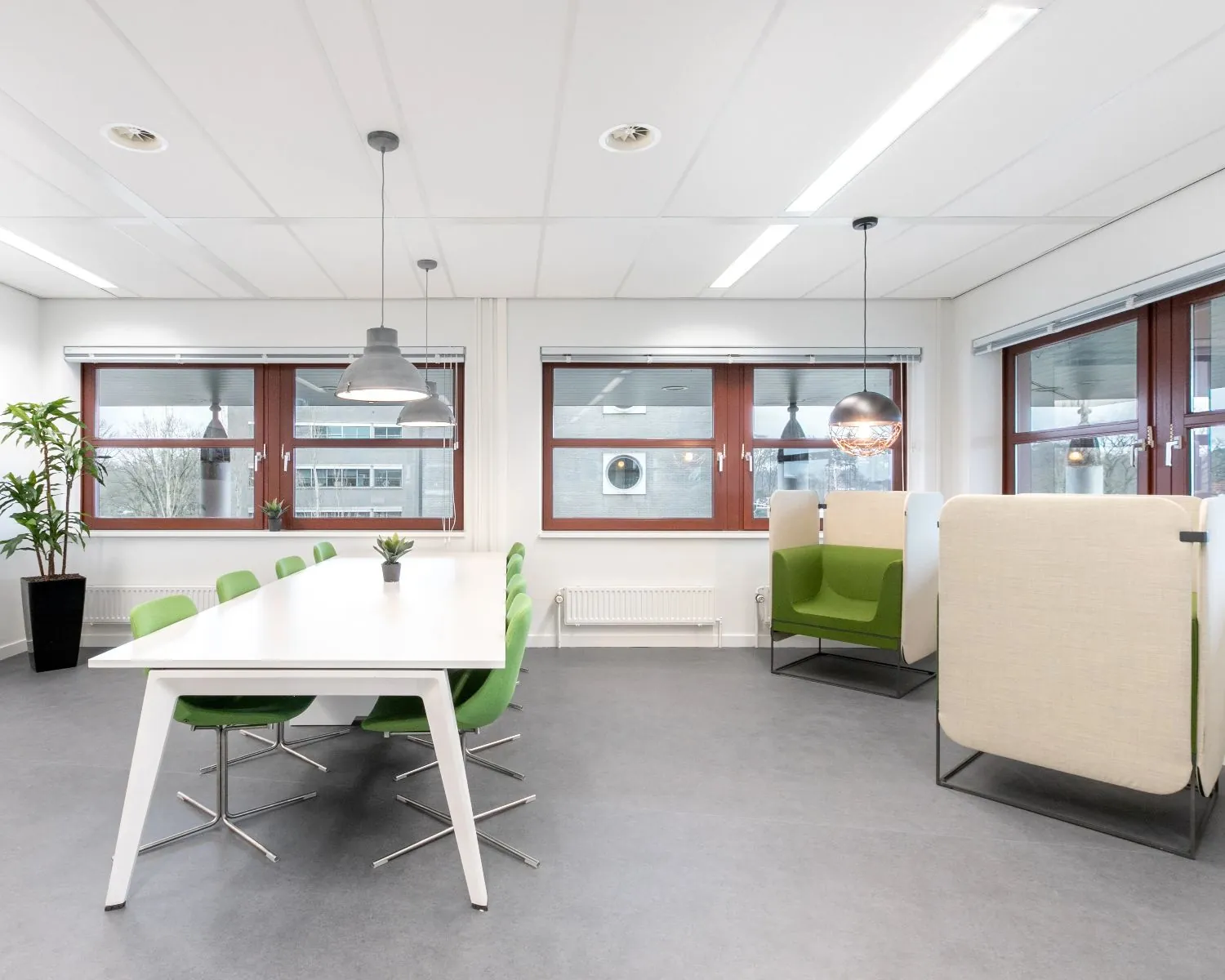 Moderne kantoorruimte in Capitool 10 Enschede met vergadertafel, groene stoelen en akoestische zitplekken bij grote ramen.