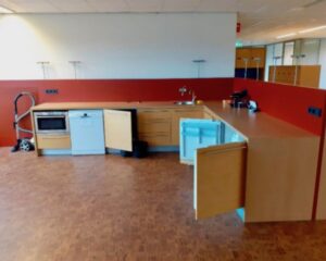 Keukenblok met inbouwapparatuur en open kastdeuren in een kantoorruimte aan de Hardwareweg in Amersfoort.