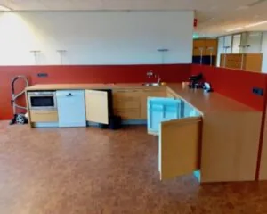 Keukenblok met inbouwapparatuur en open kastdeuren in een kantoorruimte aan de Hardwareweg in Amersfoort.
