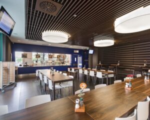Moderne bedrijfsrestaurant met houten tafels, witte stoelen en een uitgiftebalie in een kantoorruimte aan de Kronenburgsingel 525 in Arnhem.