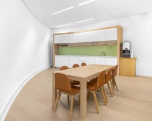 Moderne pantry met houten tafel en zes stoelen in kantoorruimte aan de Looskade 20 in Roermond.