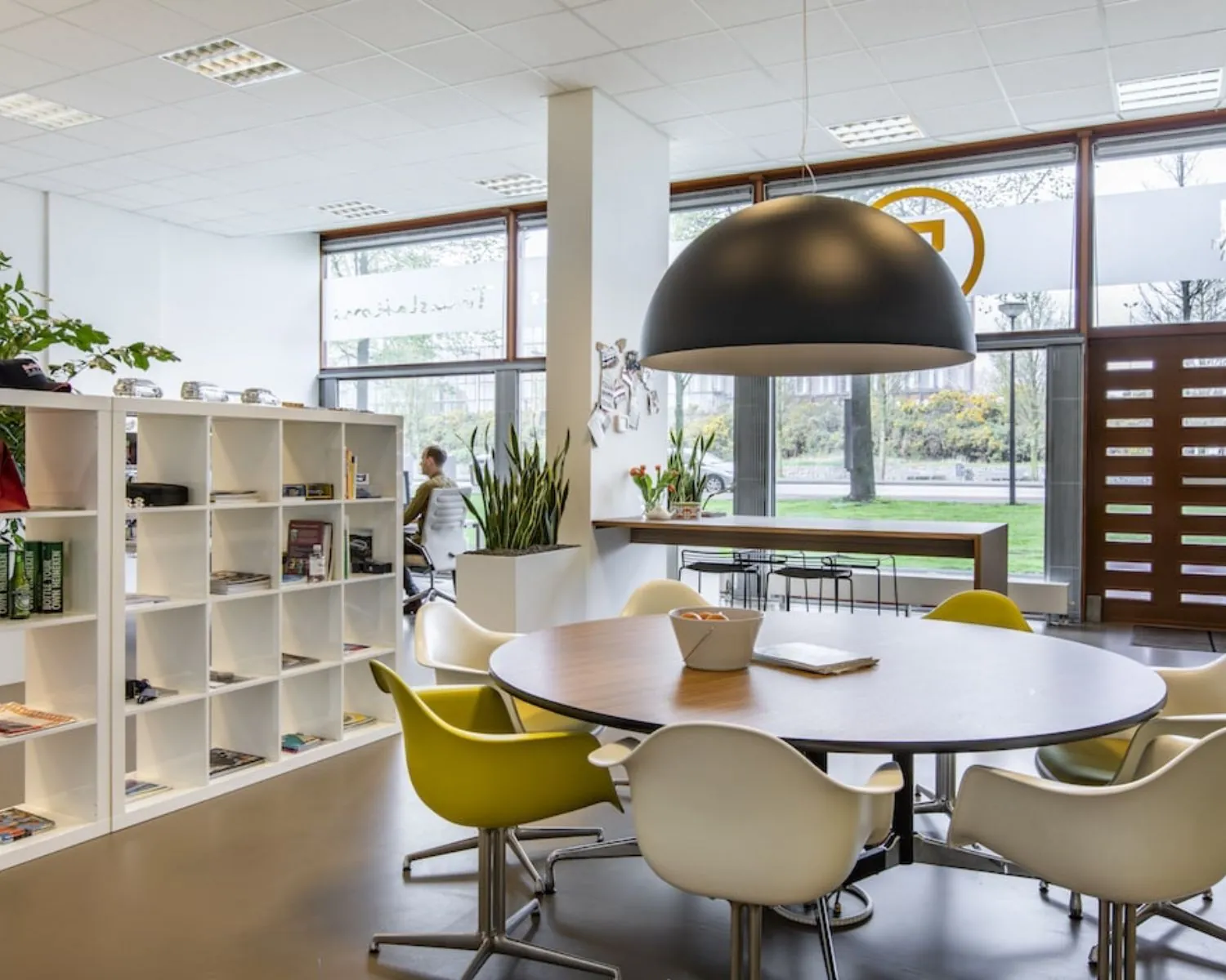 Moderne kantoorruimte aan de Panamalaan 104 in Amsterdam met ronde vergadertafel, open kast en grote raampartijen.