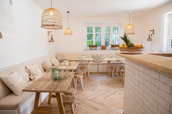 Licht en sfeervol interieur van Creativegrounds – Emmalaan met houten meubels, rieten lampen en een fruitschaal op de bar.