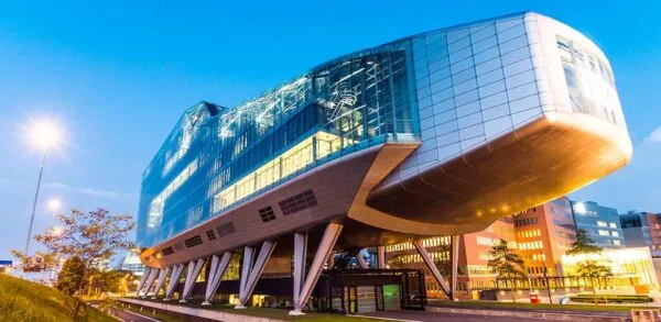 Modern kantoorgebouw aan de Amstelveenseweg in Amsterdam met futuristisch design en glazen gevel, gefotografeerd tijdens zonsondergang.