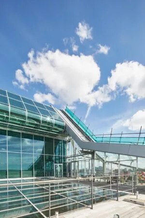 Modern glazen kantoorgebouw aan de Amstelveenseweg met een opvallend schuindak en blauwe lucht op de achtergrond.