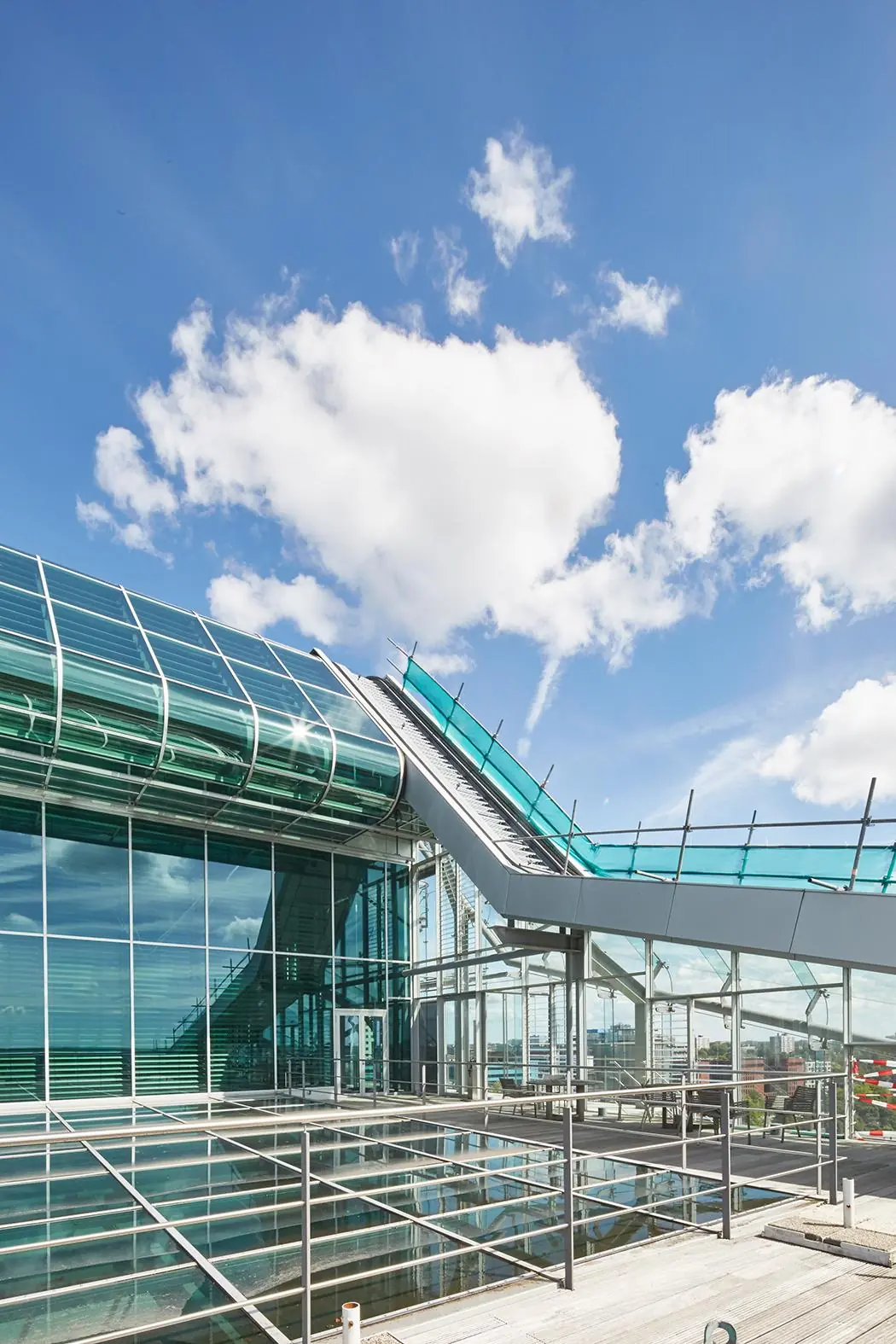 Modern glazen kantoorgebouw aan de Amstelveenseweg met een opvallend schuindak en blauwe lucht op de achtergrond.