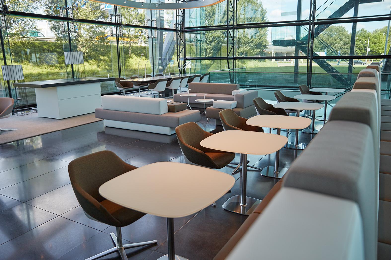 Moderne en licht ingerichte lounge- of wachtruimte aan de Amstelveenseweg met comfortabele zitplaatsen en grote glazen ramen.