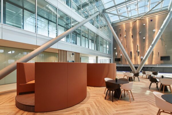 Moderne kantoorlounge aan de Amstelveenseweg met glazen dak, zitgedeelte en kunstzinnige wanddecoratie.