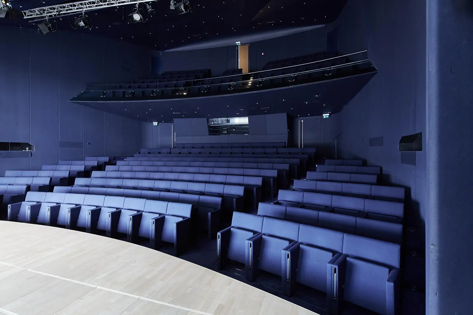 Moderne theaterzaal met blauwe stoelen en een houten podium aan de Amstelveenseweg.