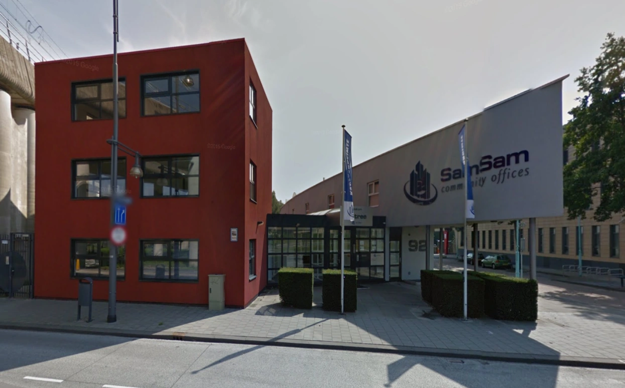 Vooraanzicht van het kantoorgebouw aan de Arlandaweg met het bord "SamSam community offices".