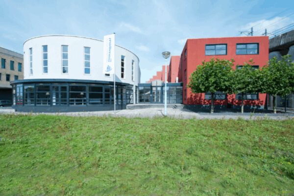 Modern kantoorgebouw aan de Arlandaweg met witte en rode gevels en een vlag met het logo van Saremma.