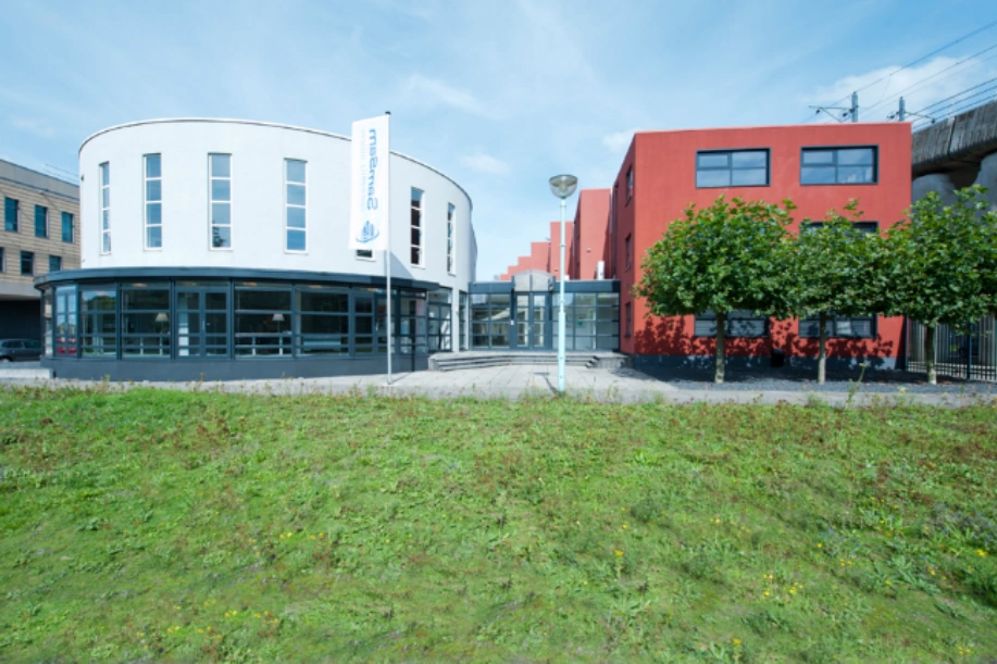 Modern kantoorgebouw aan de Arlandaweg met witte en rode gevels en een vlag met het logo van Saremma.