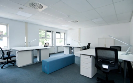 Modern en licht kantoorinterieur aan de Arlandaweg met meerdere bureaus, bureaustoelen en een blauwe zitbank.