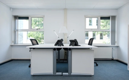 Twee werkplekken met bureaus, bureaustoelen en telefoons in een licht en modern kantoor aan de Arlandaweg.