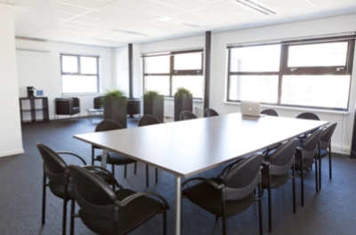 Vergaderruimte aan de Arlandaweg met een lange tafel, zwarte stoelen en veel natuurlijk licht.