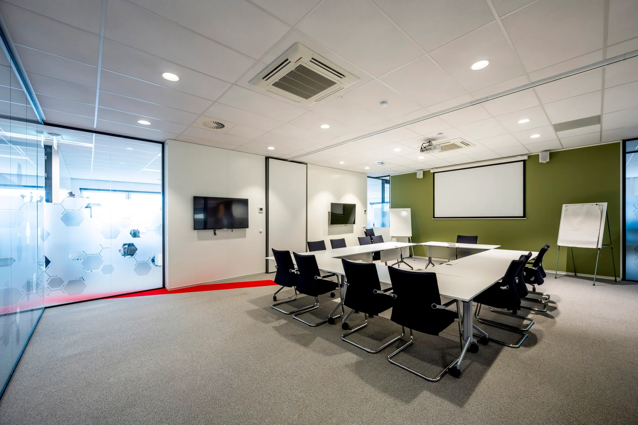 Moderne vergaderruimte met een vierkante tafel, stoelen, een projector en een flip-over.