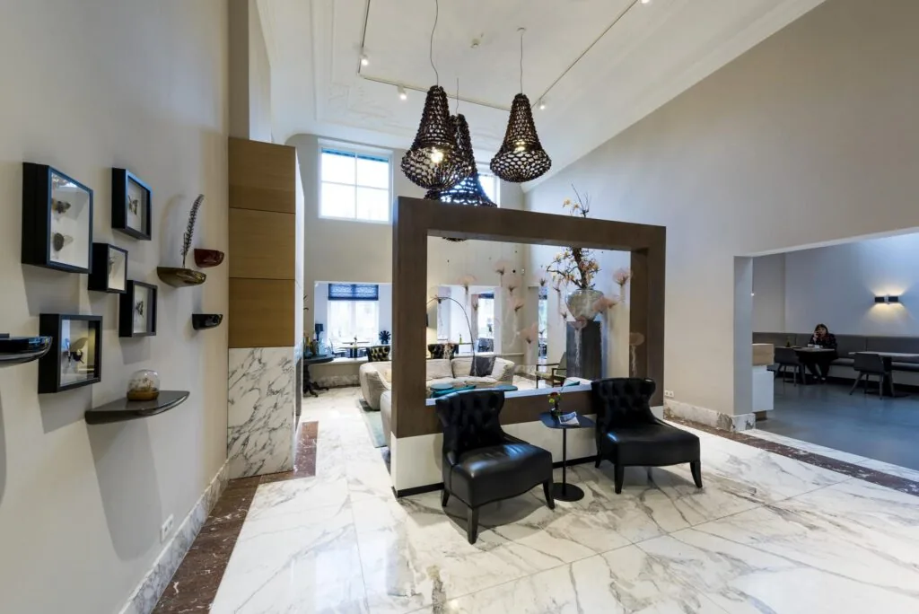 Stijlvol ingerichte hotellobby aan de Herengracht met marmeren vloer, moderne kunst aan de muur en comfortabele zitplekken.