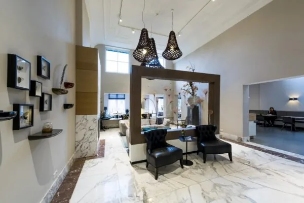 Stijlvol ingerichte hotellobby aan de Herengracht met marmeren vloer, moderne kunst aan de muur en comfortabele zitplekken.