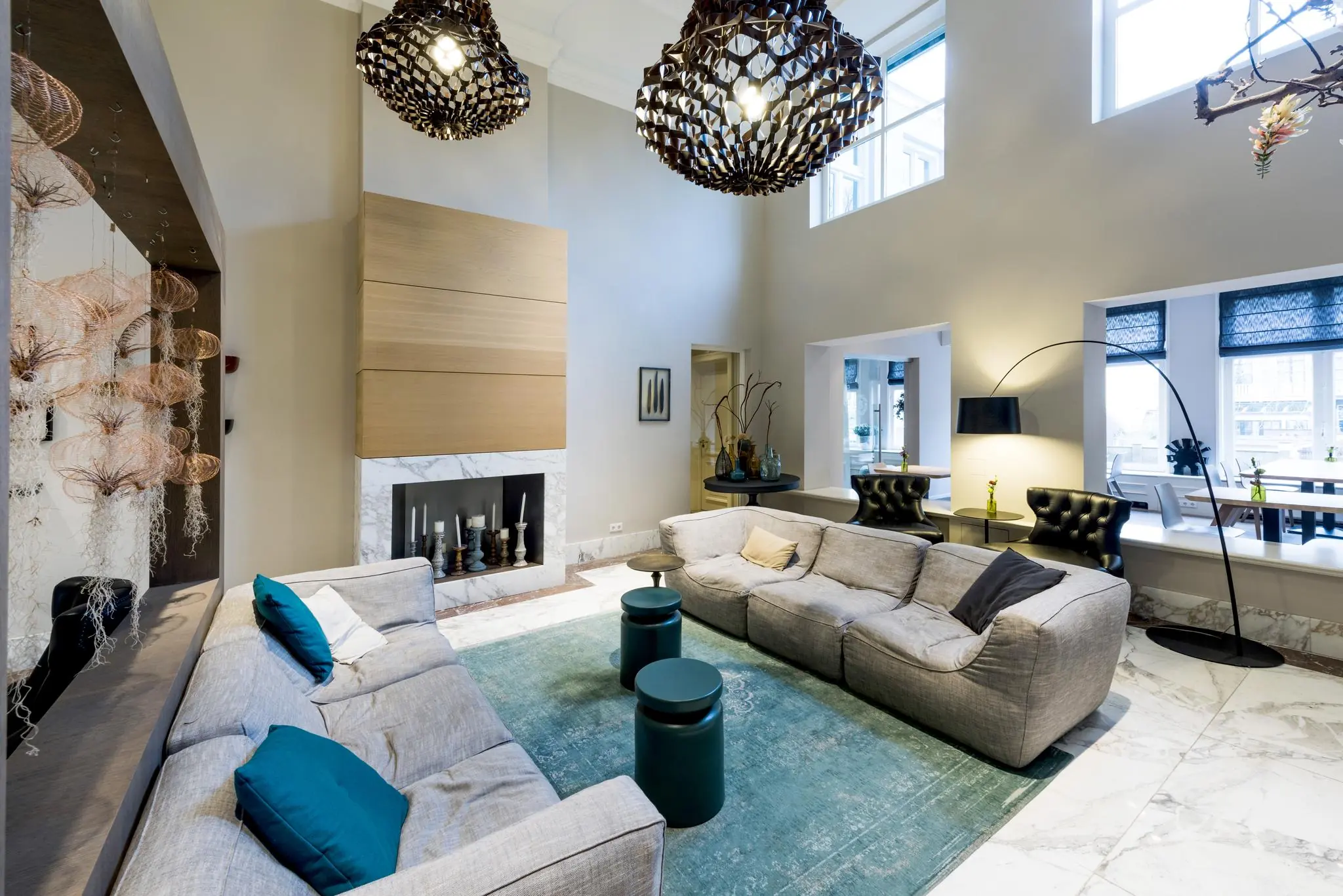 Moderne en stijlvolle lounge aan de Herengracht met grote grijze banken, designverlichting en een open haard.