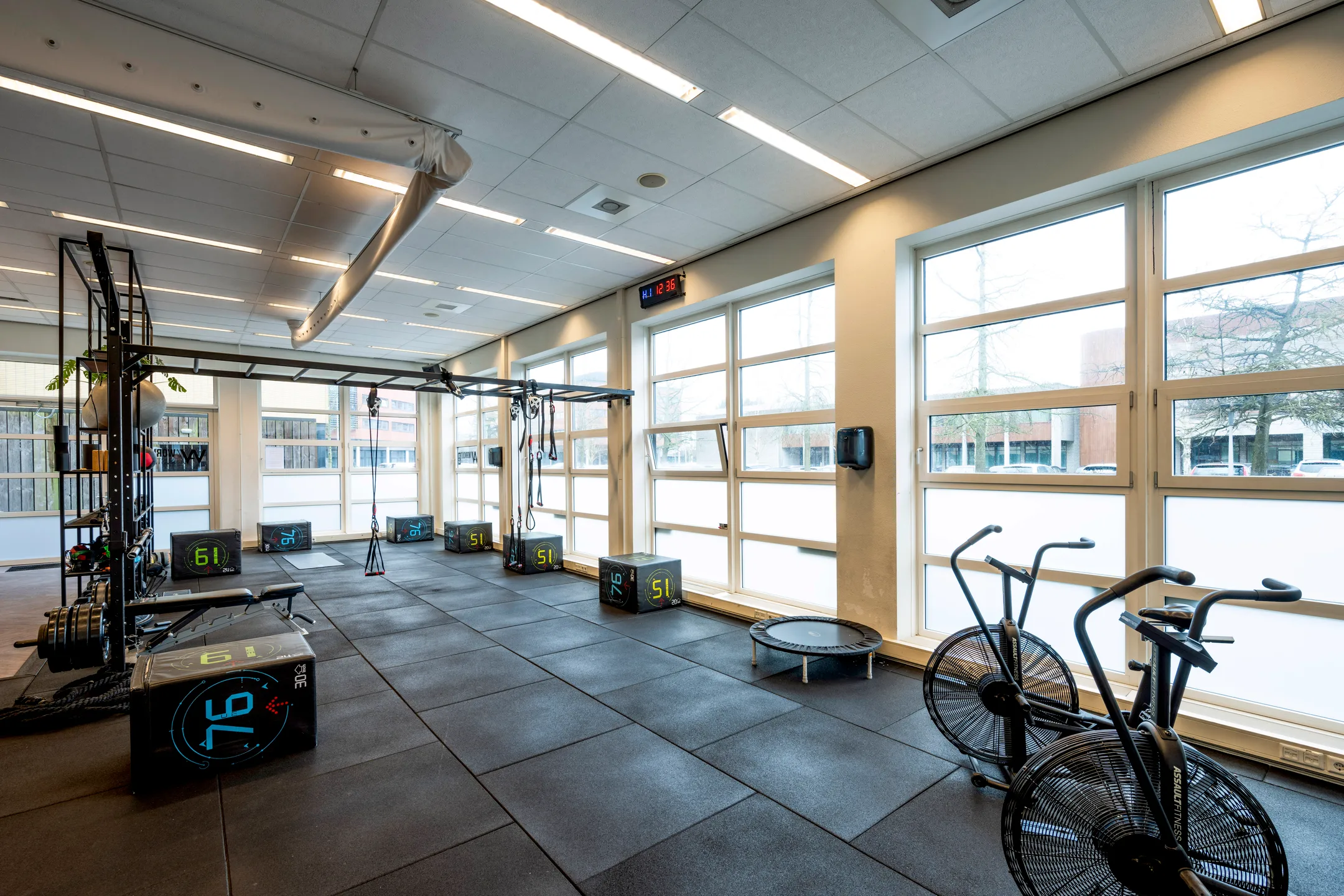 Een lichte en ruime fitnessruimte met sportapparatuur en grote ramen.